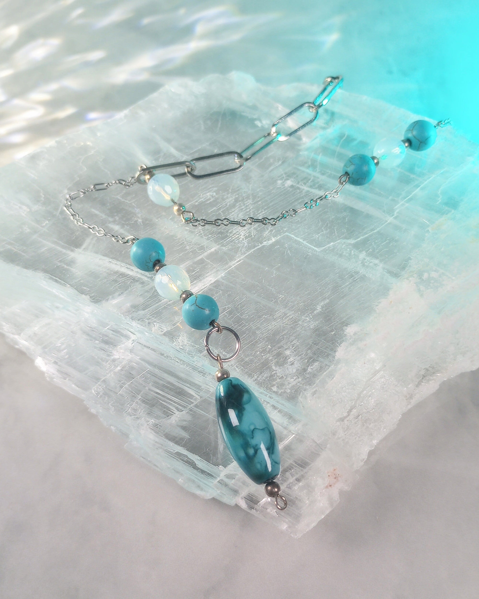 Necklace with blue beads on a light blue and white textured background