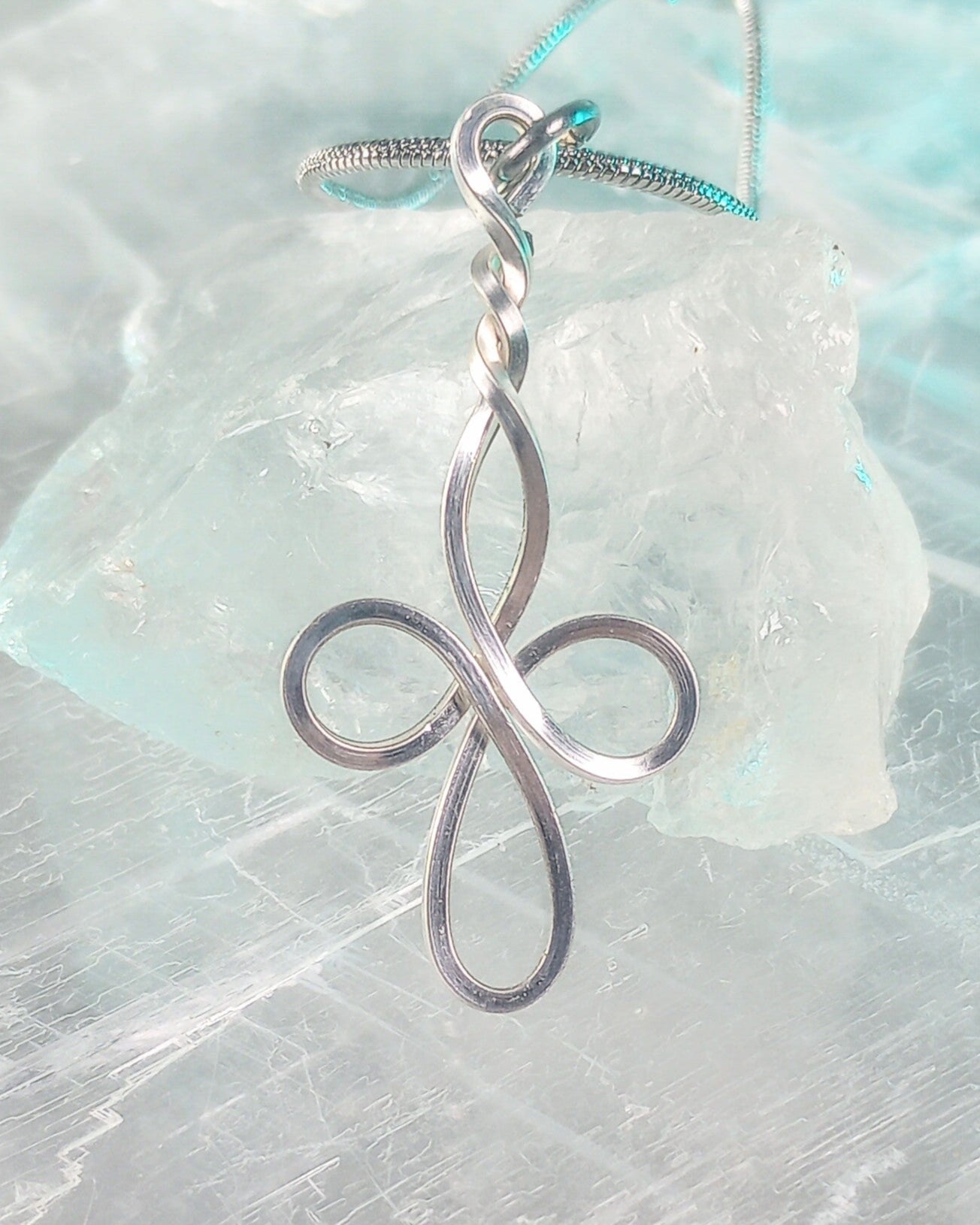 Silver cross pendant on a light blue and white textured background